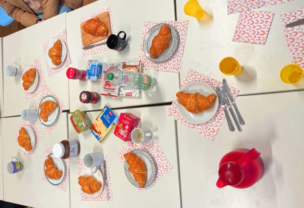 Teller, Becher und Besteck zusammen mit typisch französischen Frühstückssachen (Croissant, Marmelade und Butter)