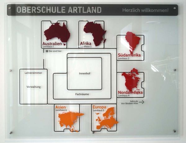 Eine Glastafel mit dem Schema der Lernhäuser der Oberschule Artland, die nach Kontinenten benannt sind
