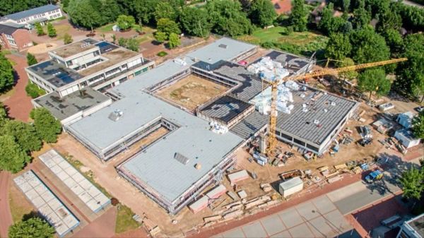 ein Luftbild des sich im Bau befindlichen Schulgebäudes, erkennbar sind der Grundriss der neuen Lernhäuser, die Mauern, Baufahrzeuge und atle Gebäude
