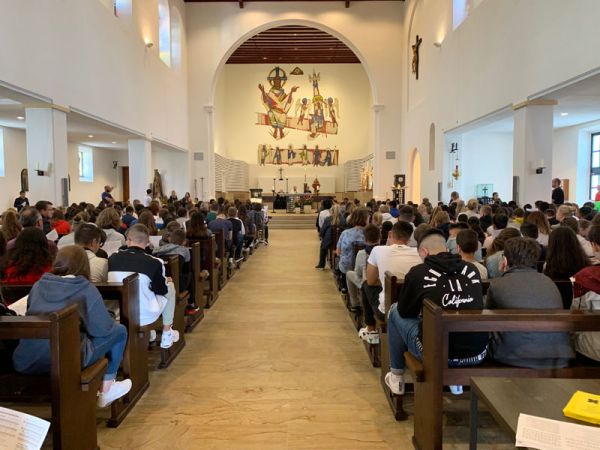 Schülerinnen und Schüler sitzen in den Kirchenbänken mit dem Blick auf den Altar