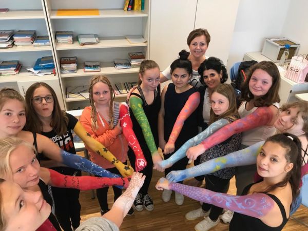 teilnehmerinnen und leiterinnen des projekts halten die arme zusammen; man erkennt die bunte bemalung der oberarme