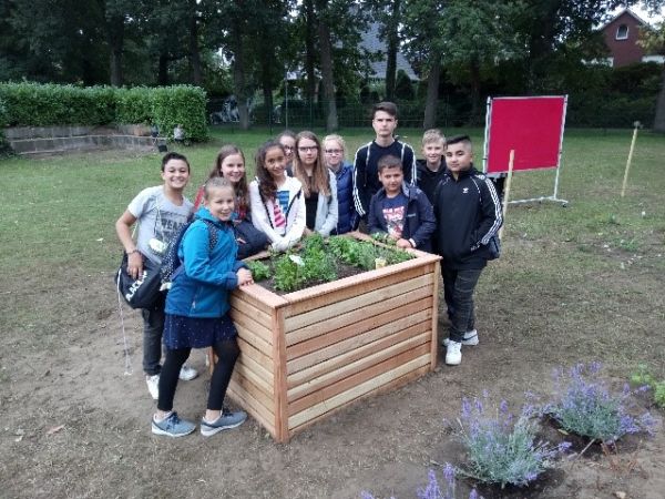 Schülerinnen und Schüler stehen um das von ihnen angelegte Hochbeet